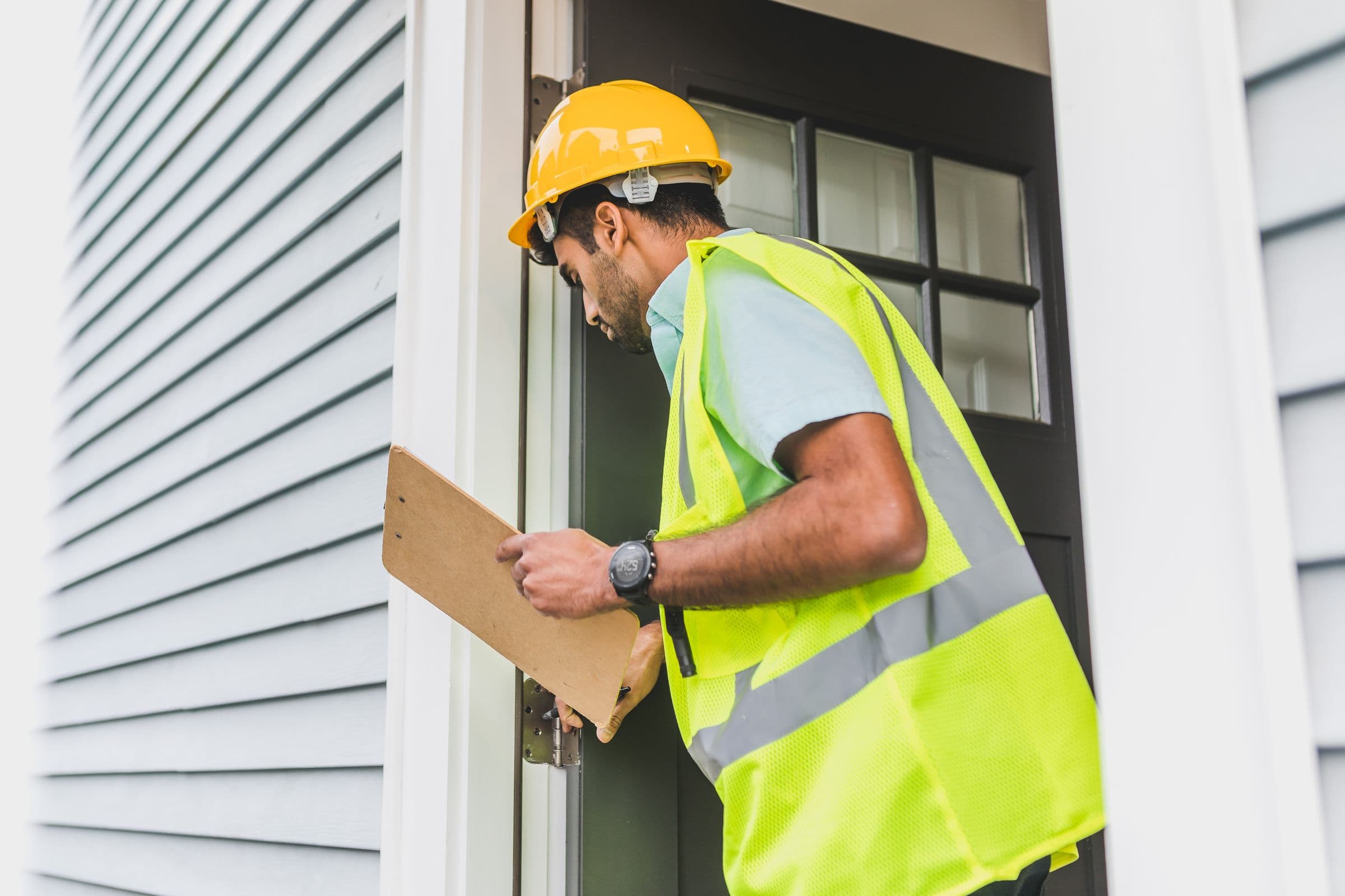 Inspecteur met helm en checklist keurt een woning